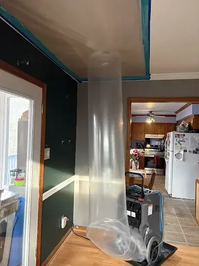Plastic containment and a dehumidifier set up in a home during a water damage dry-out