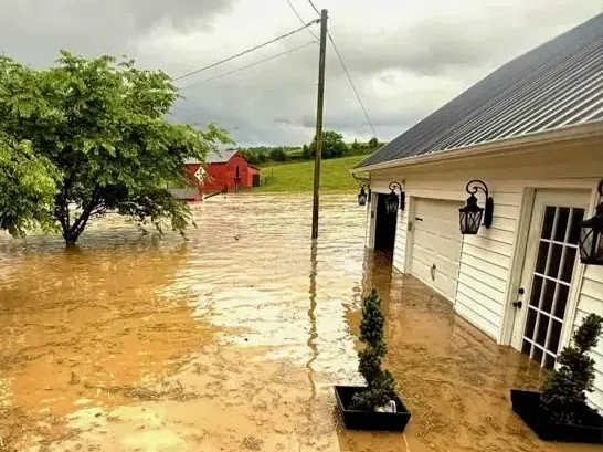 Muddy floodwater surrounding a home after a creek overflowed its banks