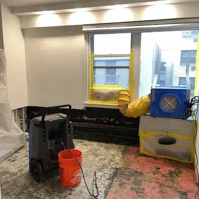 Dehumidifiers and fans drying a living room after standing water was pumped out