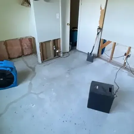 Air movers and a dehumidifier drying a room with lower drywall removed, a setup used for Mandeville homes