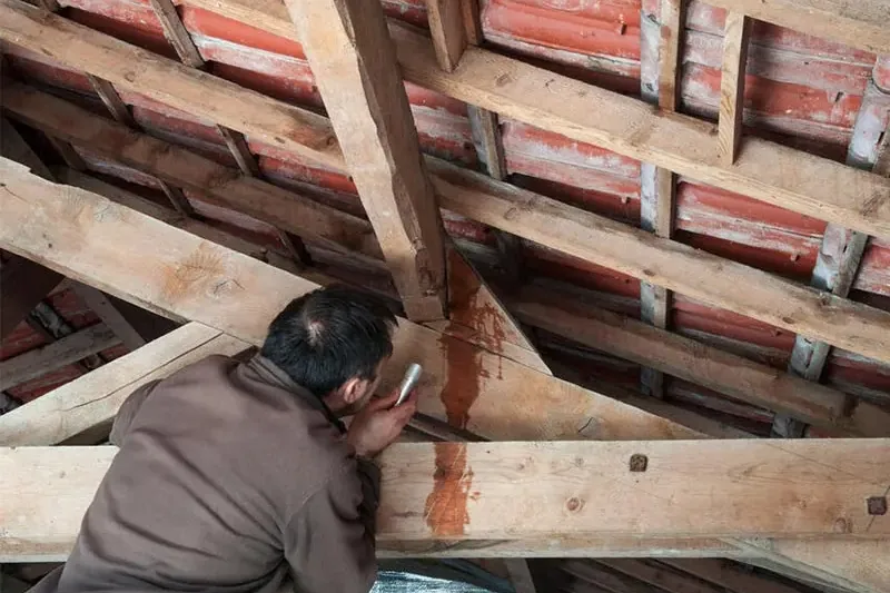 Water trail running down an attic rafter under a tile roof