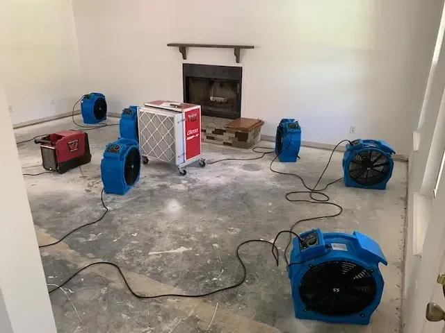 Air movers and a dehumidifier drying a room down to the slab